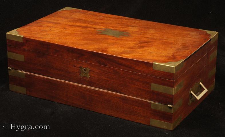 -Brass boundsolid mahogany triple opening writing box   in the military  style with countersunk carrying handles  by Austen of Dublin: the fitted compartmentalized  interior has a document wallet,   secret drawers,  a replacement velvet writing surface , and working lock with key, Circa 1830 Enlarge Picture